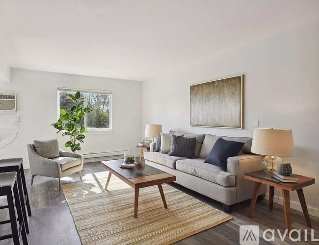 A living room with a grey couch, a wooden coffee table, and a large painting on the wall.