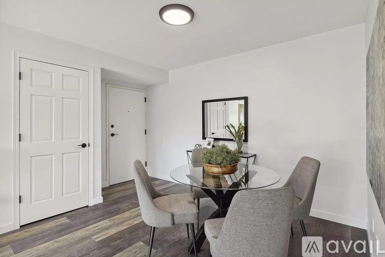 A dining room with a glass table and grey chairs.