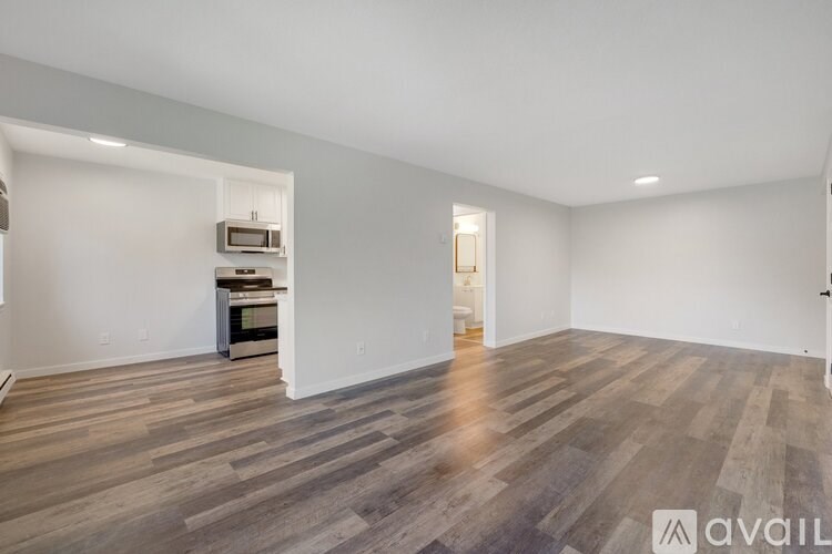A spacious room with wooden flooring and white walls.