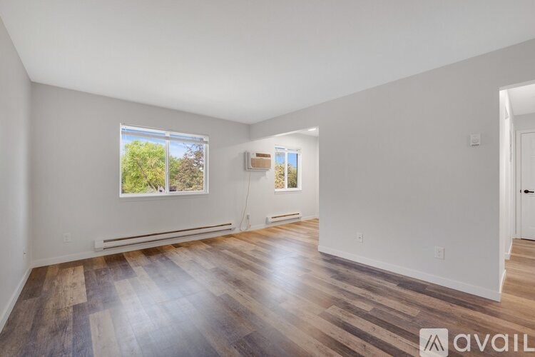A room with wooden flooring and a window showing trees outside.