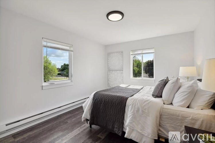 A bedroom with a large bed and a window overlooking a tree-filled street.