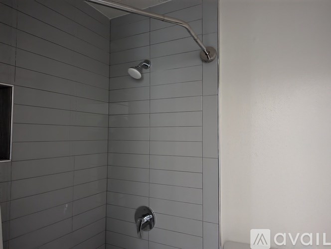 A shower with a wall of tiles and a hose attached to the wall.