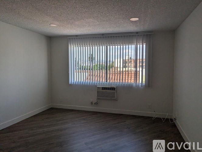 A room with a window covered by blinds and a wooden floor.