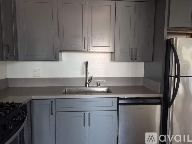 A kitchen with grey cabinets and a stainless steel dishwasher.