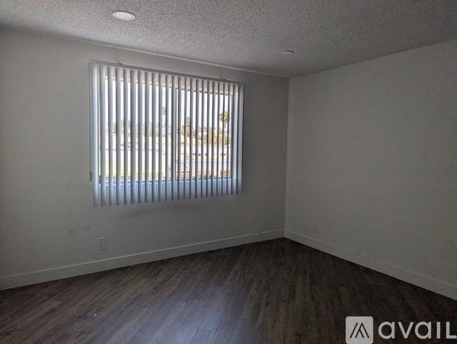A room with a window covered by vertical blinds.
