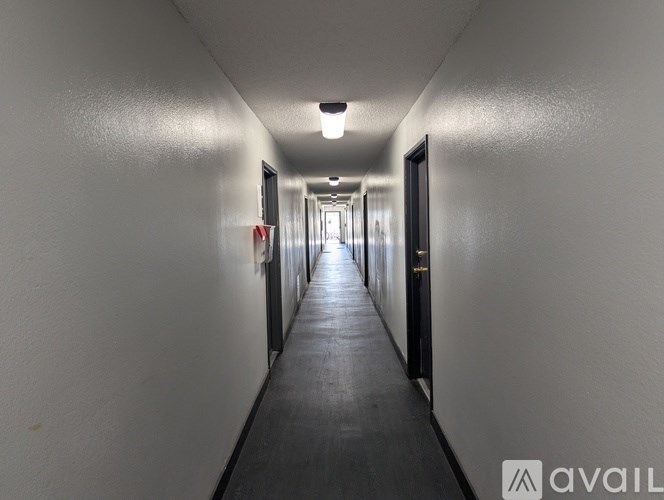 A long, narrow hallway with doors on both sides and a light on the ceiling.