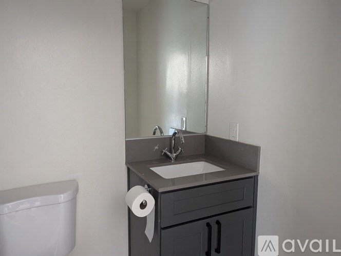 A bathroom with a sink, mirror, and toilet paper roll.