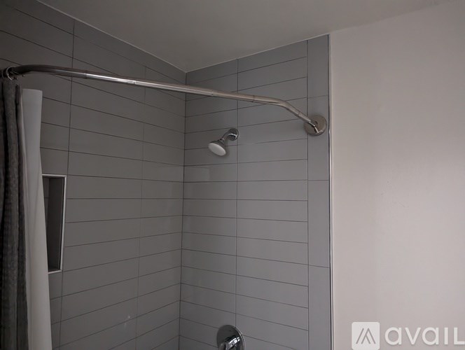A shower with a silver shower head and a silver grab bar.