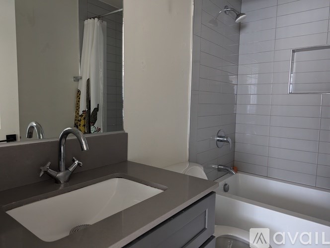 A bathroom with a sink, mirror, and shower.