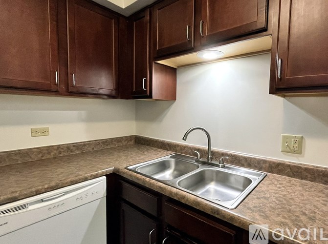A kitchen with brown cabinets and a white dishwasher.