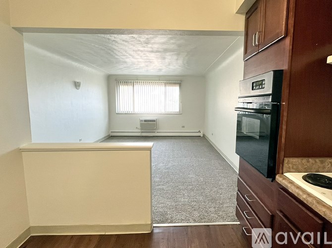 A kitchen area with a refrigerator, oven, and a window with blinds.