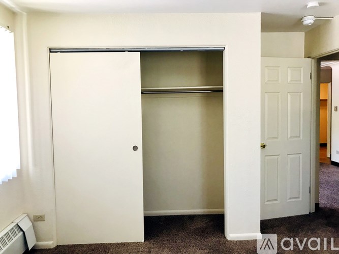 A white closet with a shelf and a door with a handle.