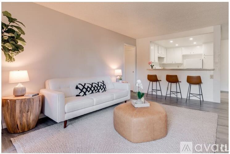 A living room with a white couch, a wooden side table, and a grey rug.