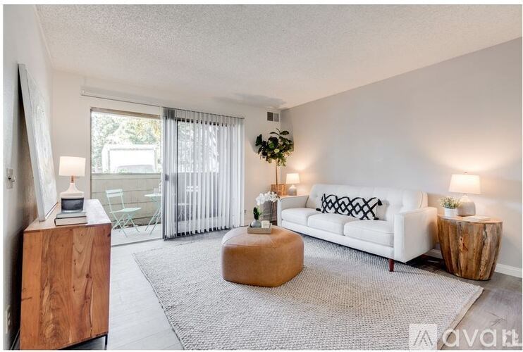 A living room with a white couch, a wooden cabinet, and a grey rug.