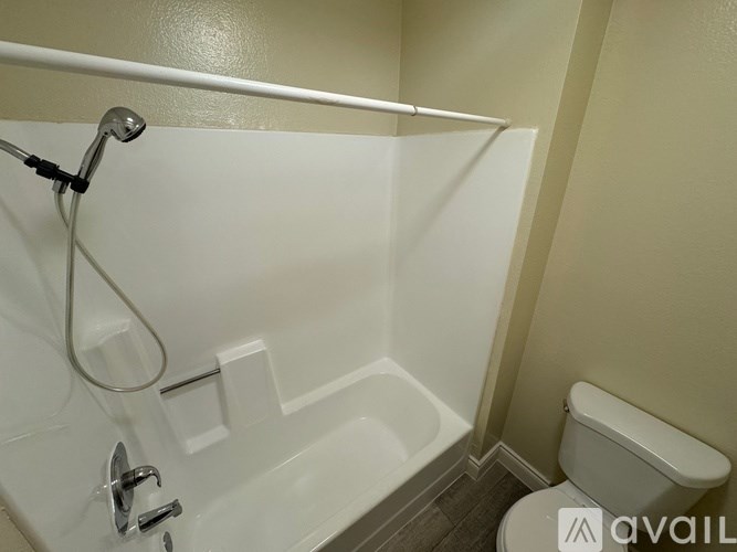 A white bathtub with a shower head and a toilet in a bathroom.