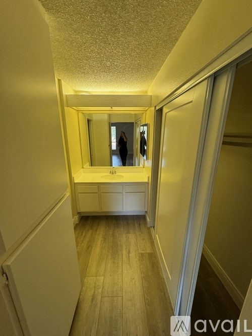 A bathroom with a sink and mirror in the middle of a hallway.