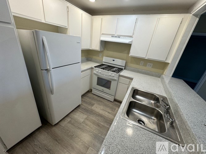 A kitchen with a white refrigerator and a stainless steel sink.