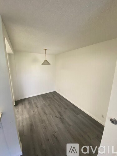 A room with wooden flooring and a light hanging from the ceiling.