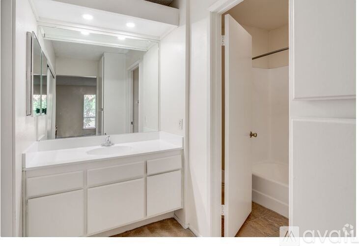 A white bathroom with a sink, mirror, and cabinets.