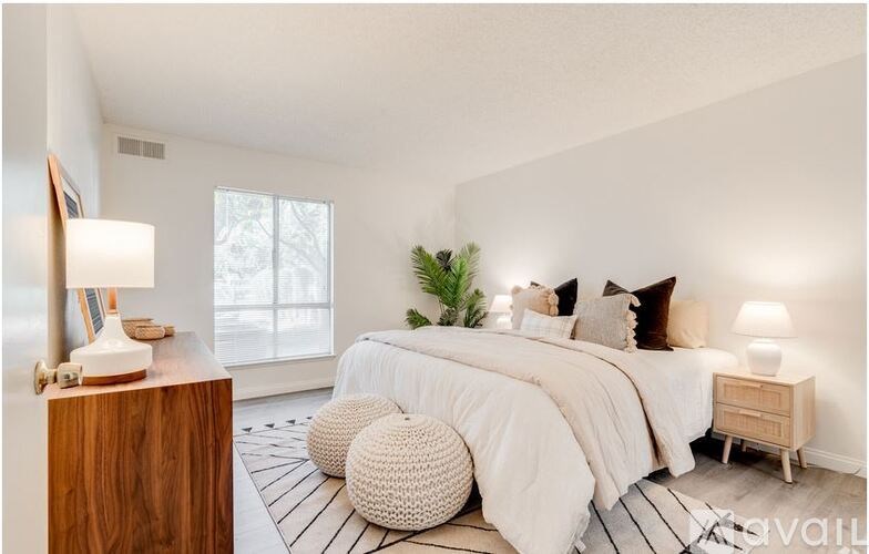 A bedroom with a large bed, a wooden nightstand, and a plant on the bedside table.