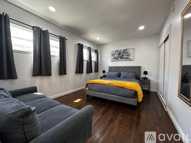 A bedroom with a large bed and a window with black curtains.
