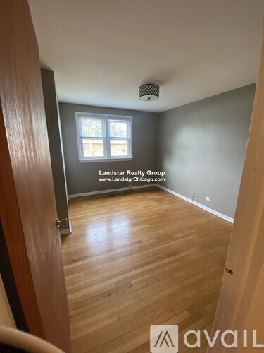 A room with wooden flooring and a window, branded with Landstar Realty Group.