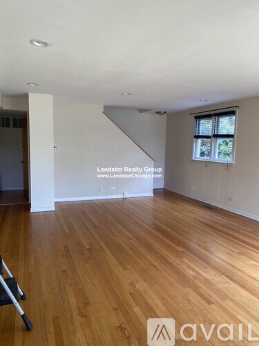 A room with wooden flooring and a window with blinds.