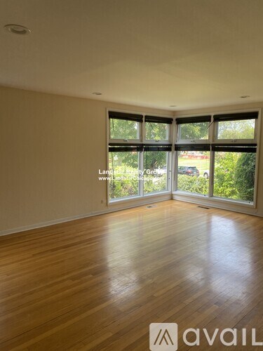 A room with wooden flooring and large windows.