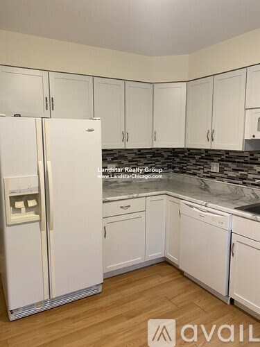 A kitchen with white cabinets and a refrigerator.