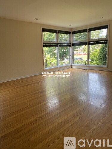 A room with wooden flooring and large windows.