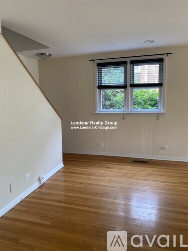 A room with wooden flooring and a window with blinds.