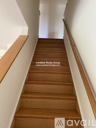 A flight of wooden stairs with a white wall on the side.