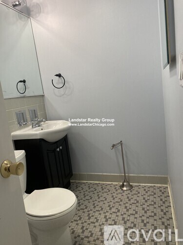 A bathroom with a toilet, sink, and a shower head.