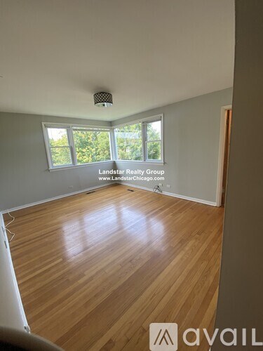 A room with wooden flooring and a window overlooking trees.