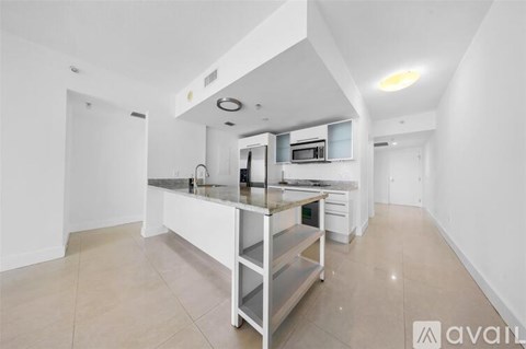 A kitchen with white cabinets and a marble countertop.