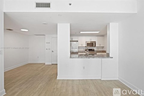 A spacious kitchen with white cabinets and a wooden floor.