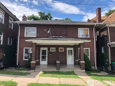 A red brick house with a white door and a small porch.