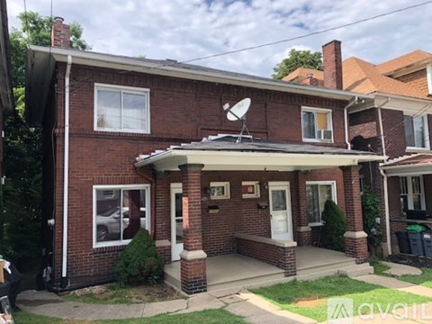 A red brick house with a white door and a satellite dish on the roof.
