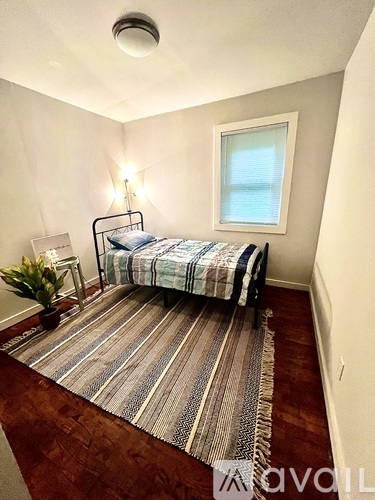 A bedroom with a bed, nightstand, and window.