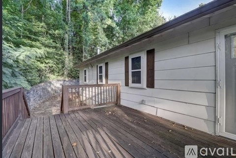 A wooden deck with a house and trees in the background.