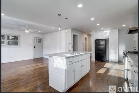 A kitchen with white cabinets and a black refrigerator.