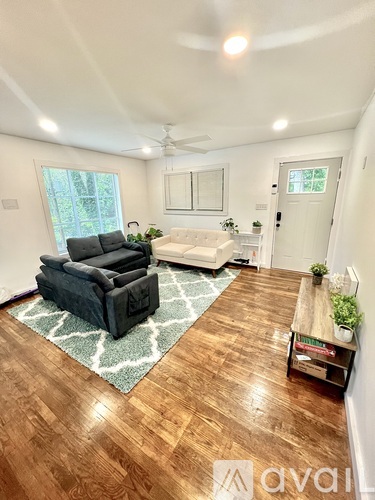 A living room with a black couch and a rug.