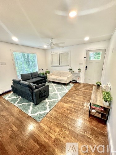 A living room with a black couch and a rug.