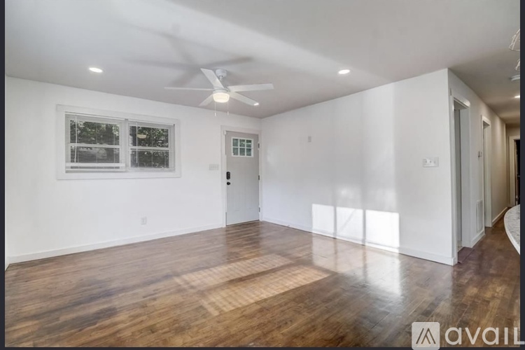 A spacious room with wooden floors and a ceiling fan.