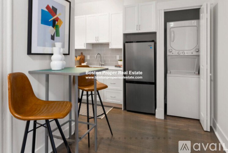 A kitchen with a fridge and a table with two chairs.
