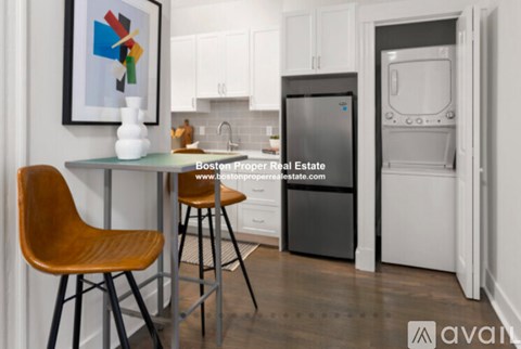 A kitchen with a fridge and a table with two chairs.