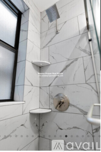 A bathroom with a marble wall and a shower area.