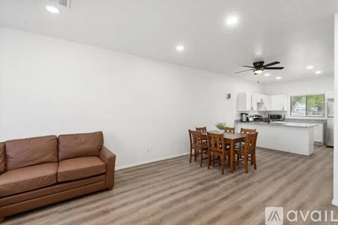 A brown couch is in a living room with a dining table and chairs.