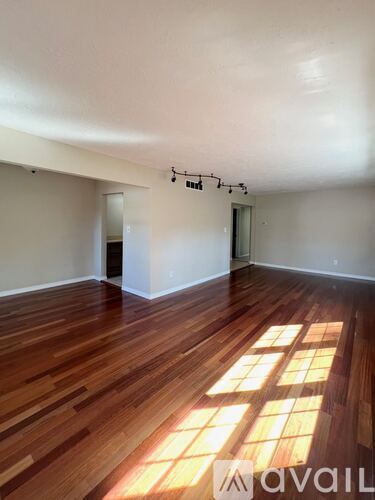 A room with wooden floors and a large window letting in sunlight.