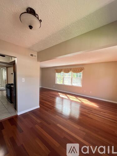 A room with wooden floors and a window with curtains.